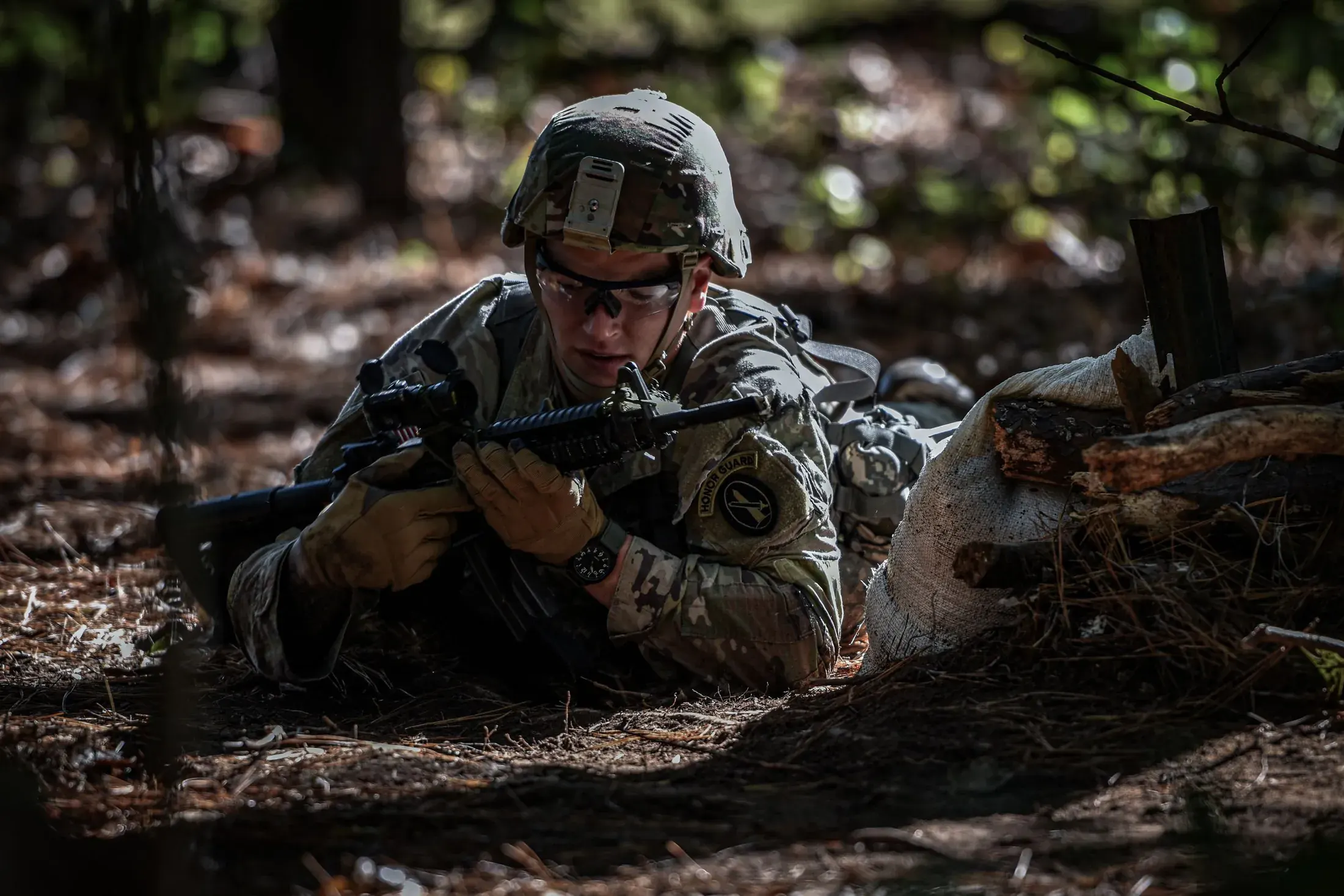 Soldier in camouflage aiming a rifle during a field exercise