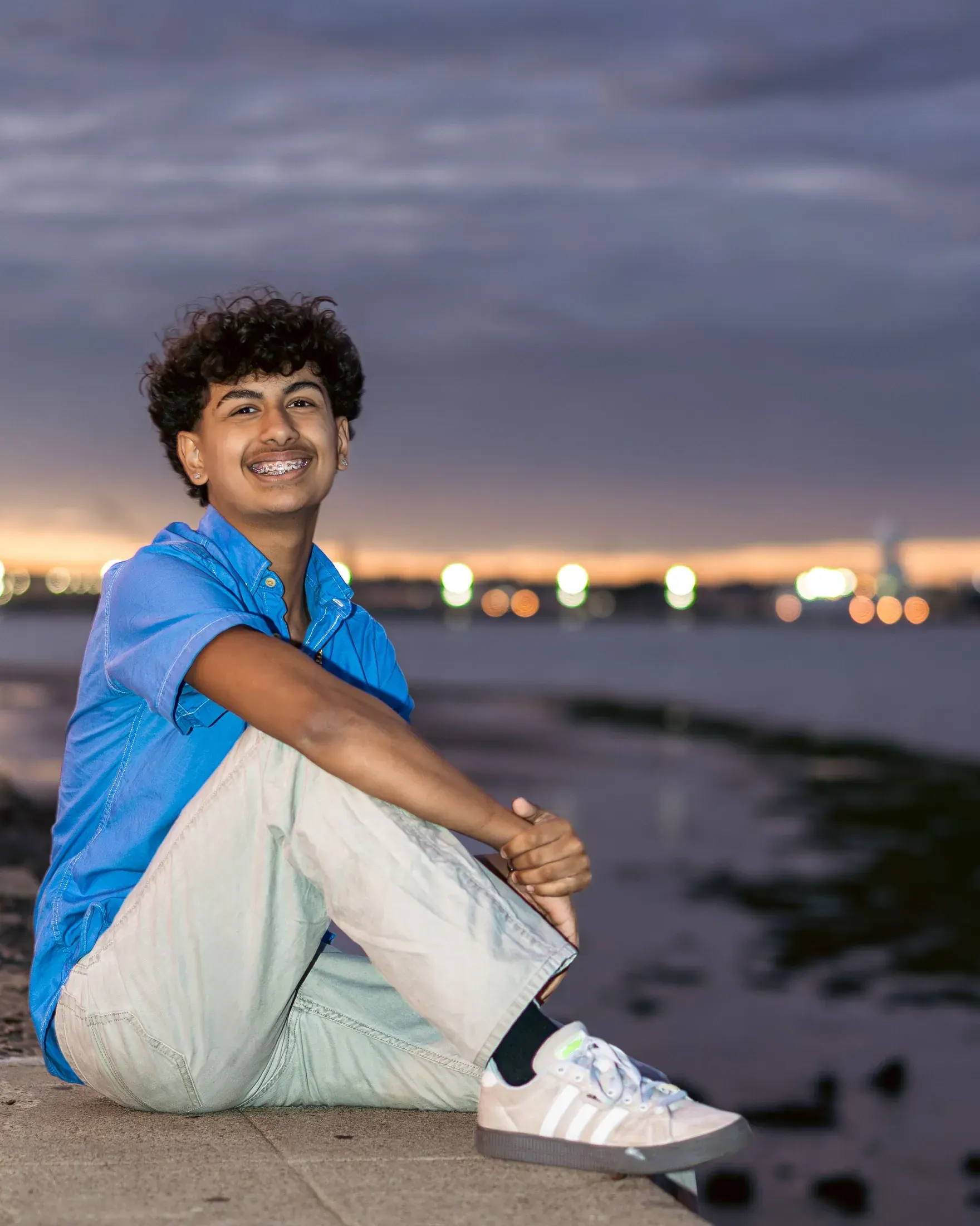 Young man sitting on the shoreline at twilight