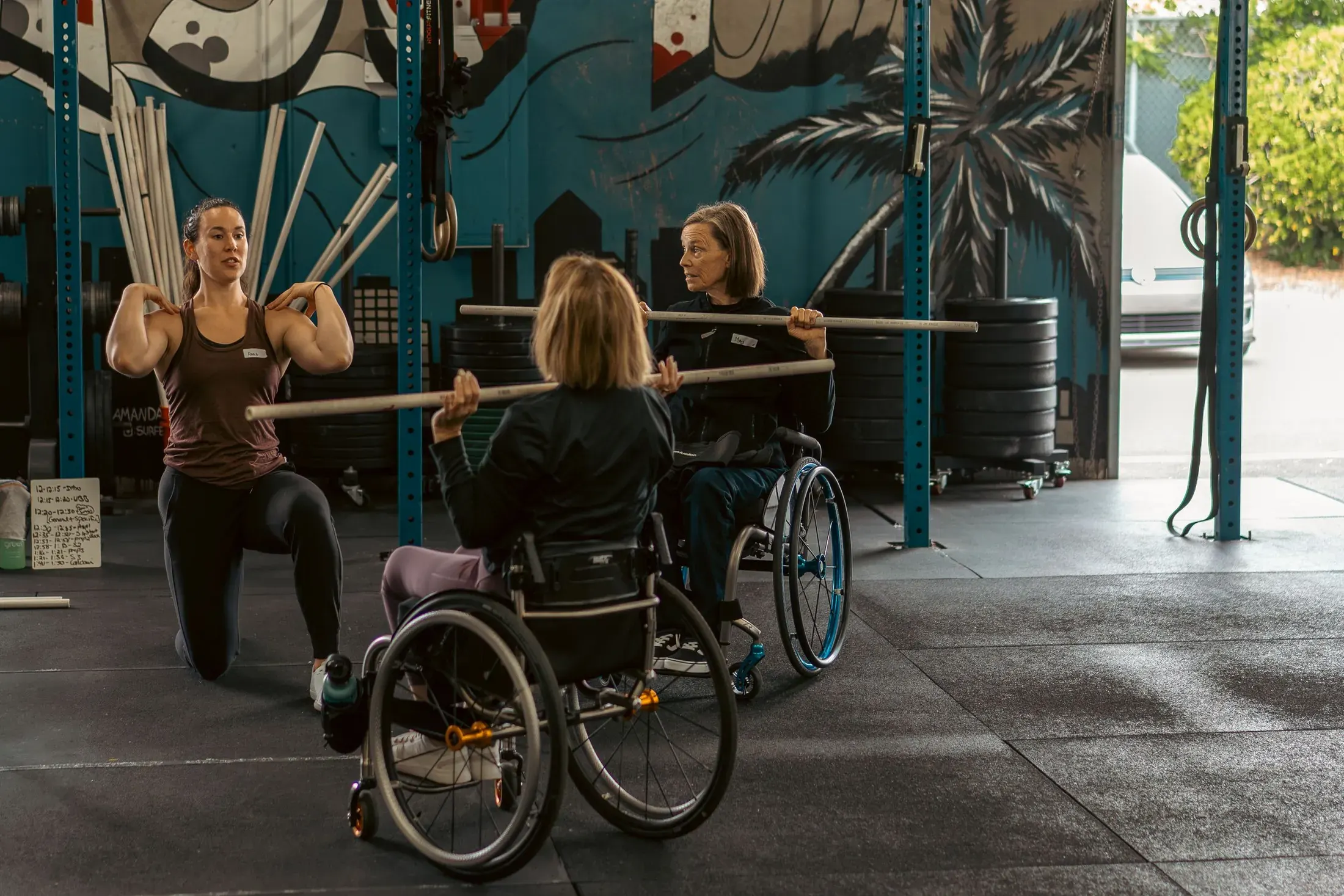 Athletes training with barbells in front of a mural