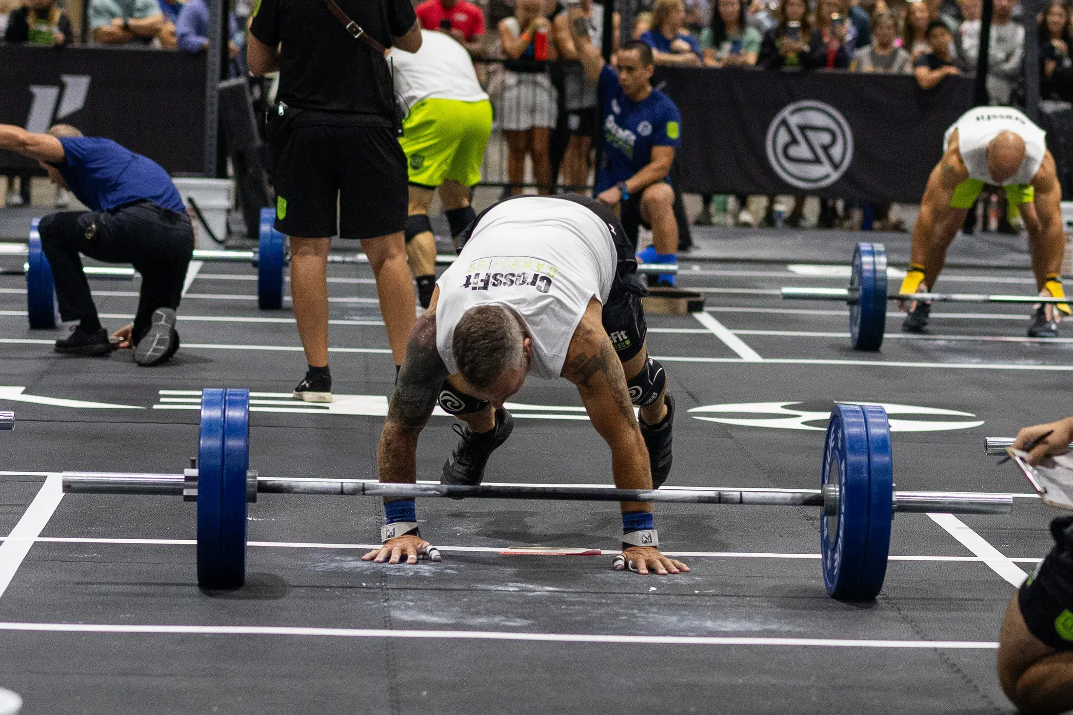Competitor chalking up over the barbell at the CrossFit Games