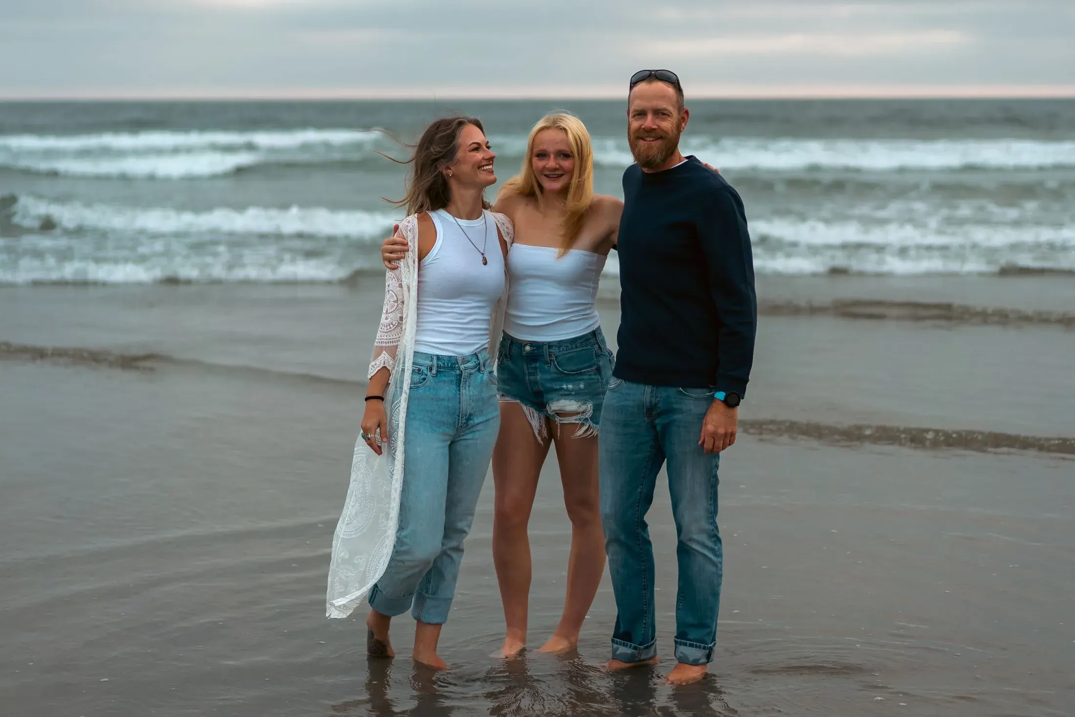 Family standing together in the shallow surf