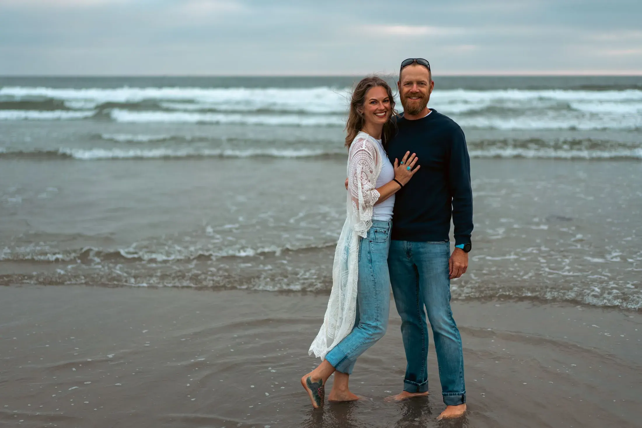 Couple standing barefoot in the surf at the beach