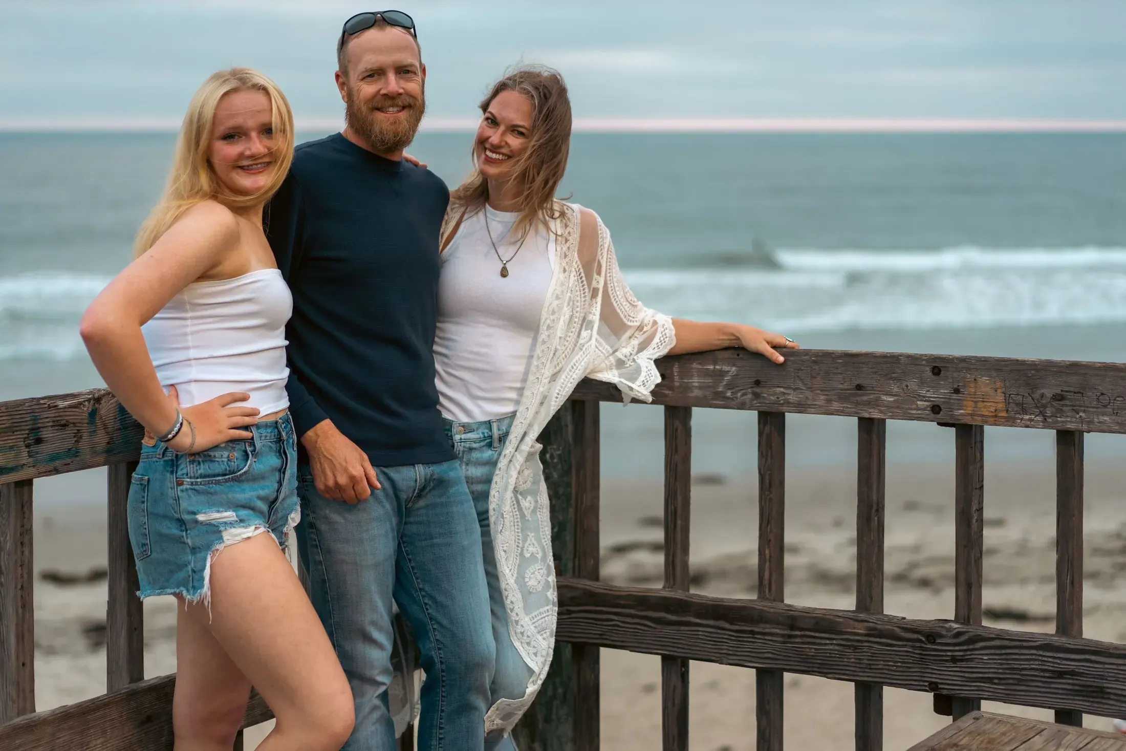 Father with his two daughters at a beach railing