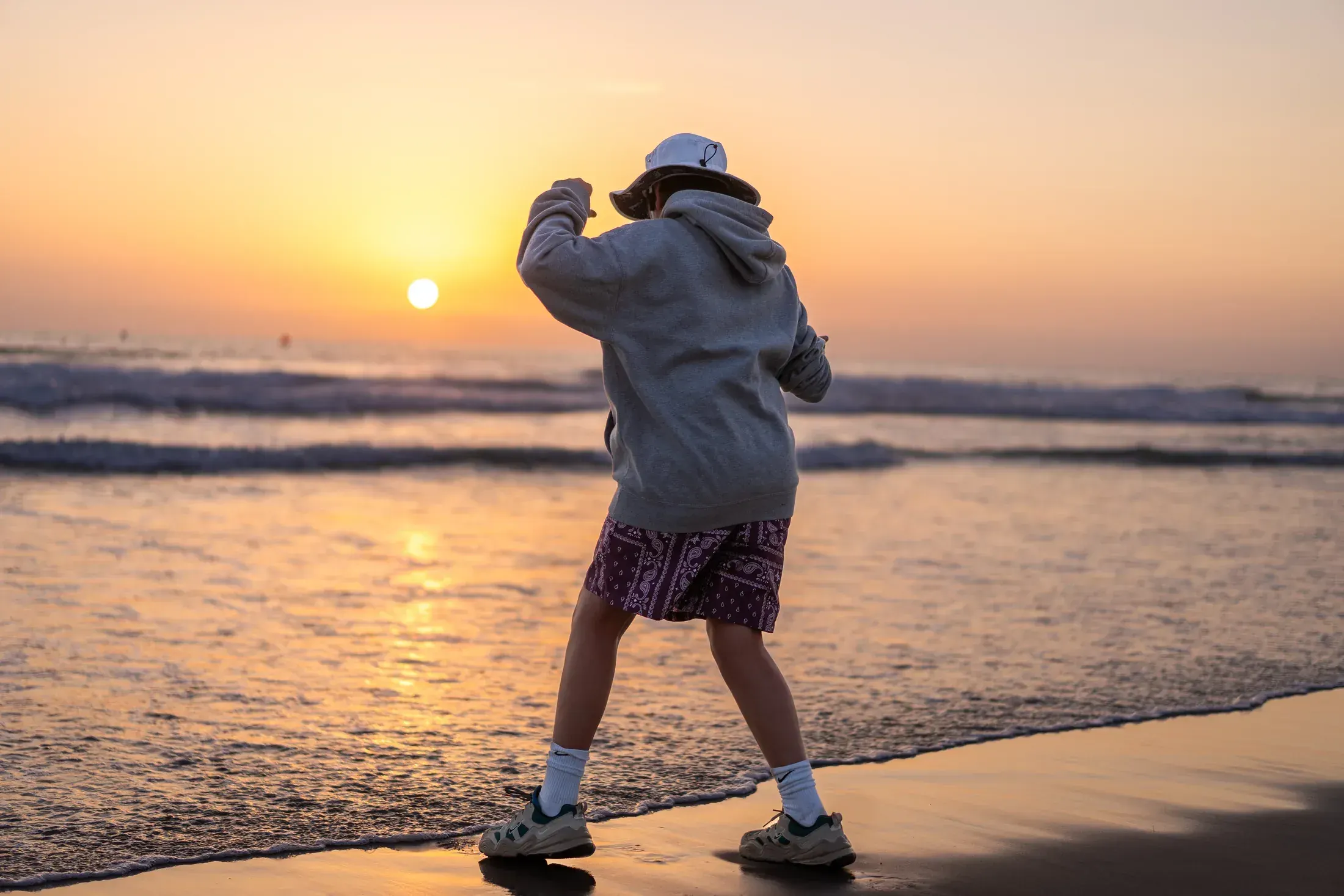 Kid playing in the waves at sunset