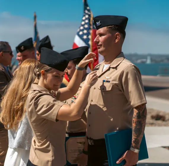 Family member pinning a new rank on a sailor