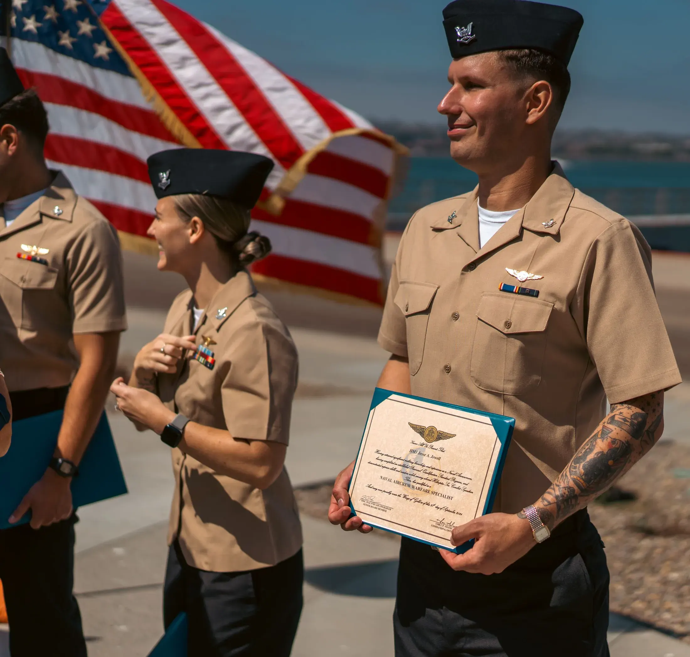 Family member pinning a new rank on a sailor in front of an American flag