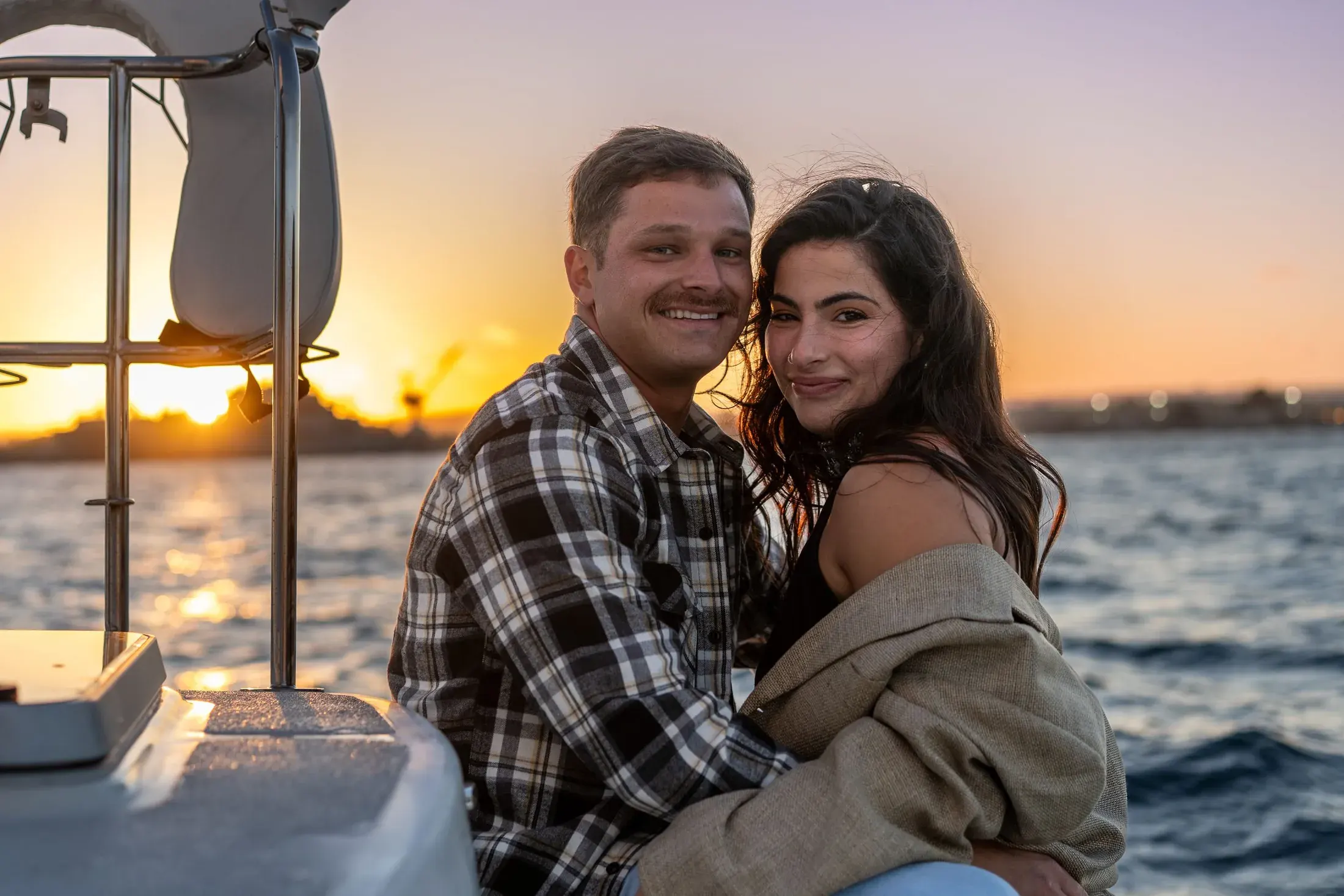 Couple cuddling on a boat at sunset