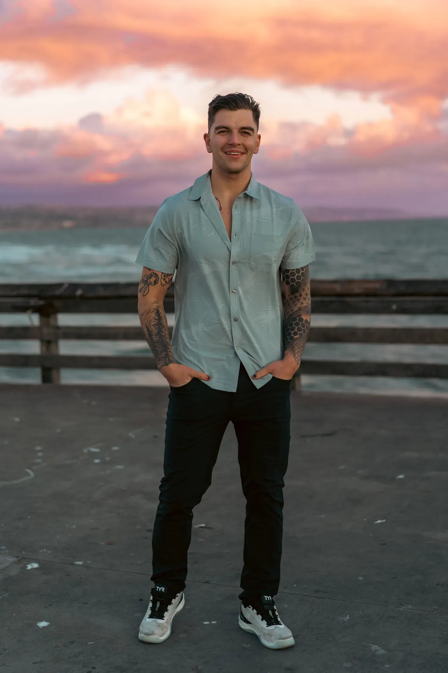 Keegan Holt, San Diego photographer, standing on a pier at sunset