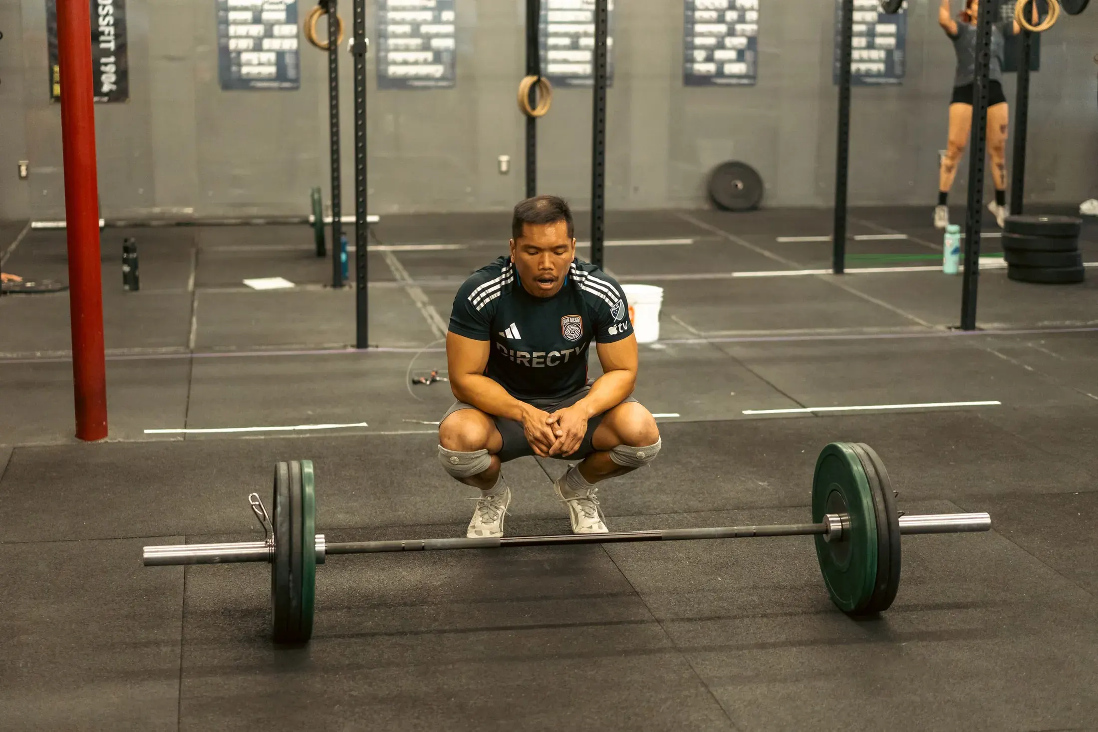 Coach squatting behind a barbell