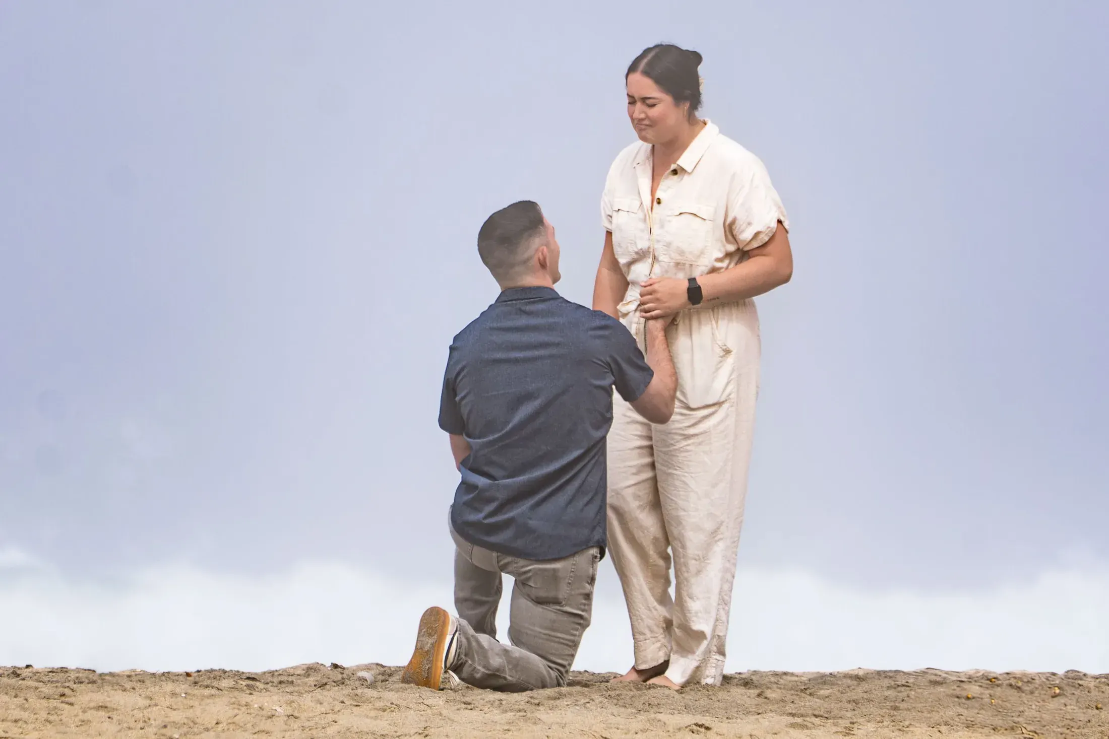 Man kneeling to propose on a cliff above the clouds