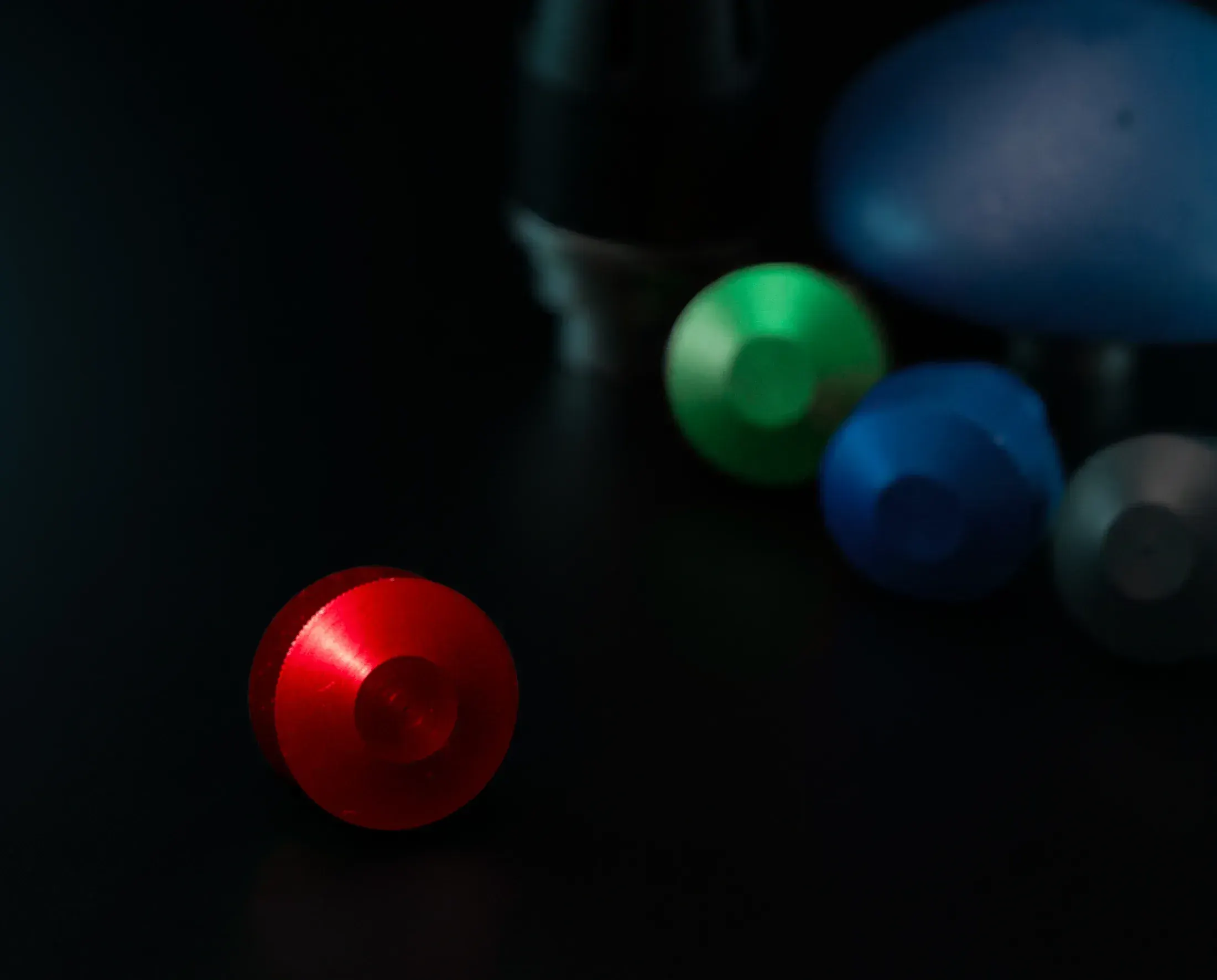 Red and blue machined aluminum parts on a black surface
