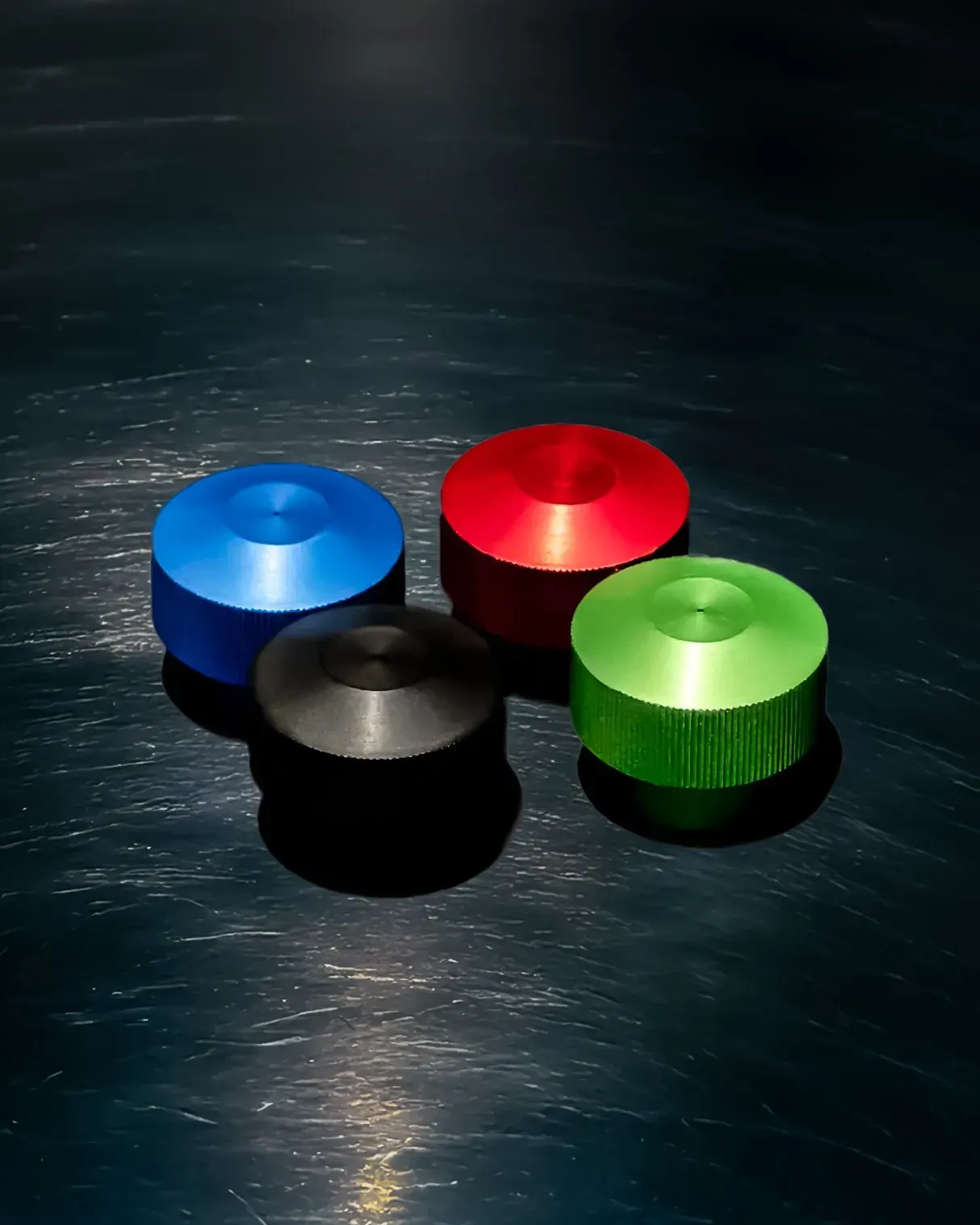 Colorful machined aluminum pieces on a dark surface