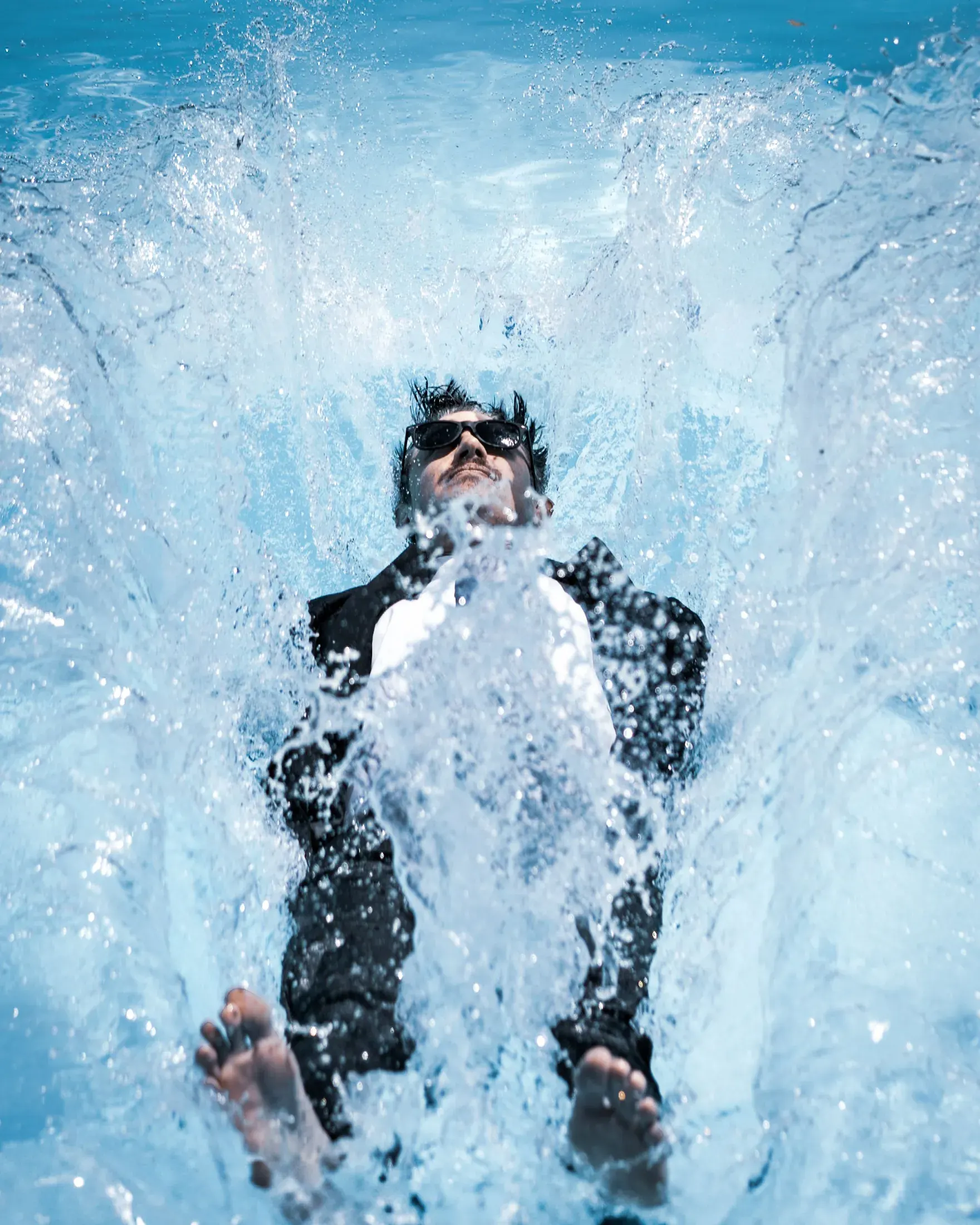 Man in a suit falling backward into a pool with a big splash