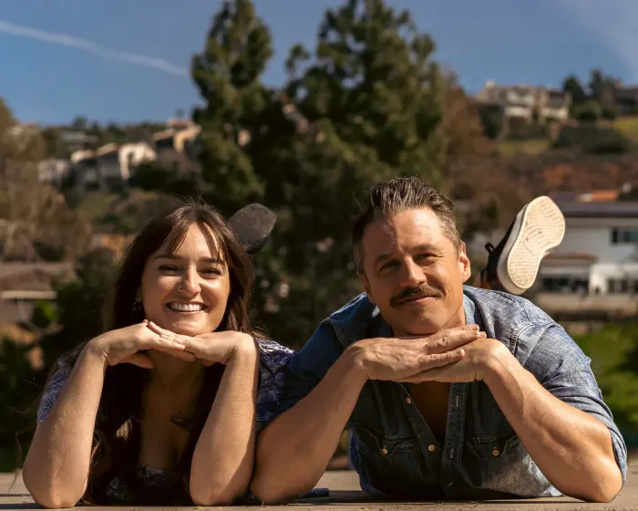 Couple resting their chins on their hands and smiling in the sun