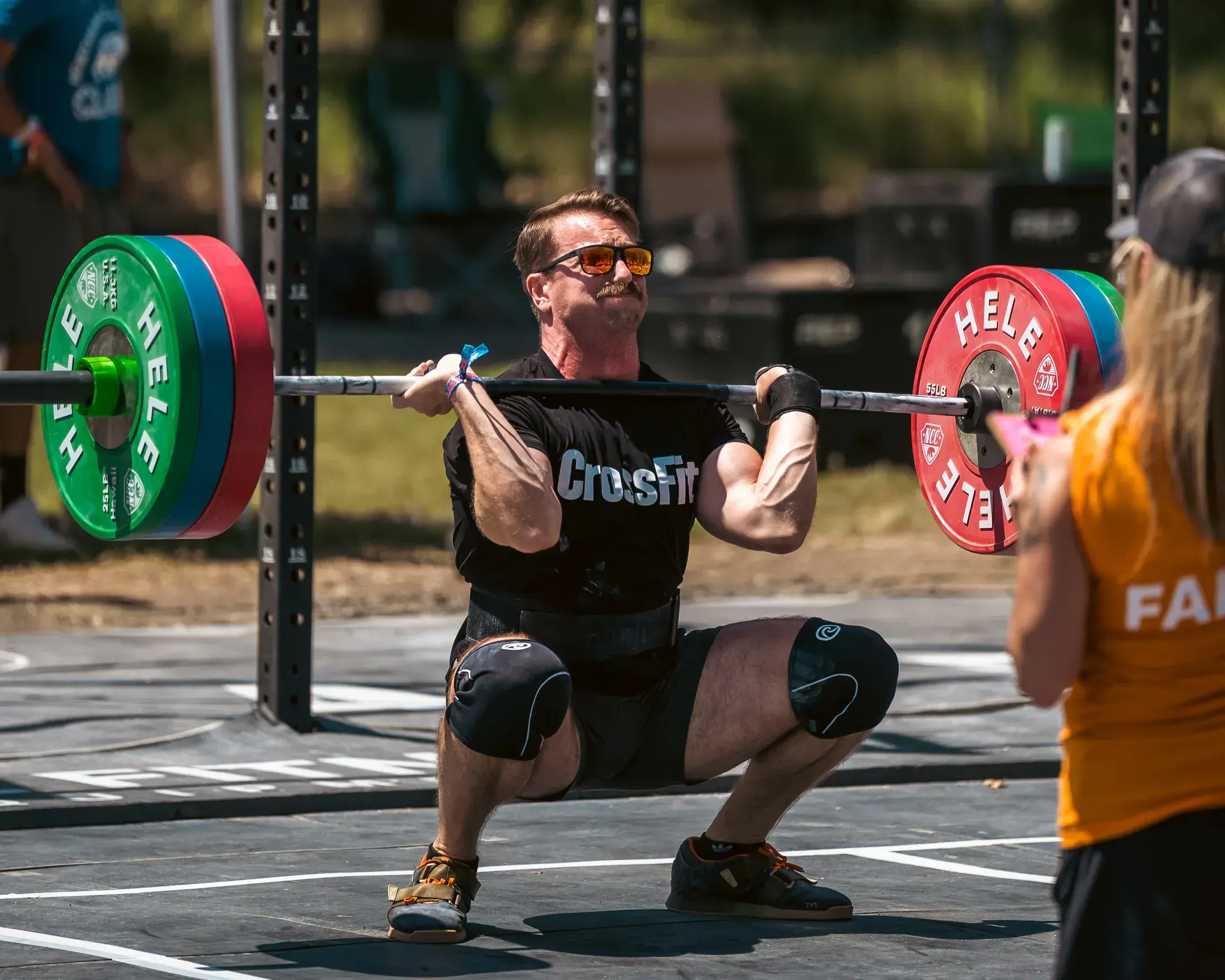 Athlete squatting a loaded barbell at an outdoor competition