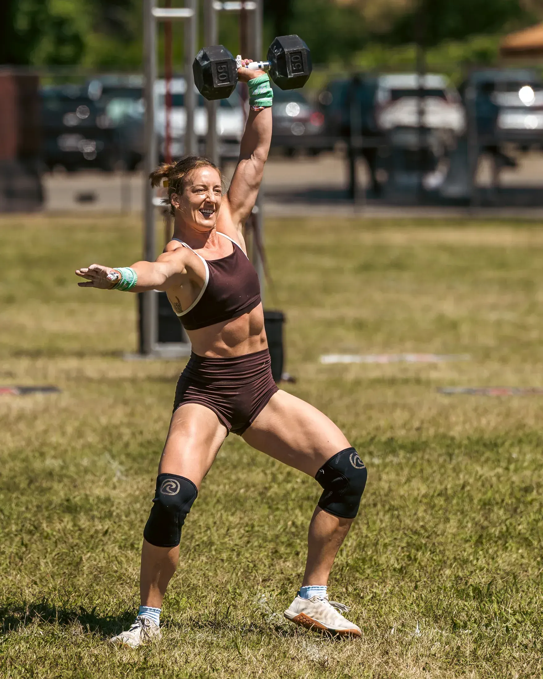Athlete pressing a dumbbell overhead on the grass