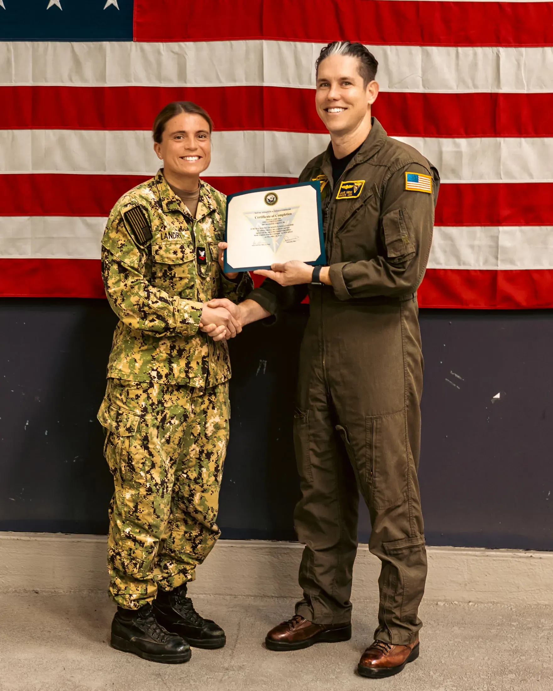 Service member receiving a certificate in front of an American flag