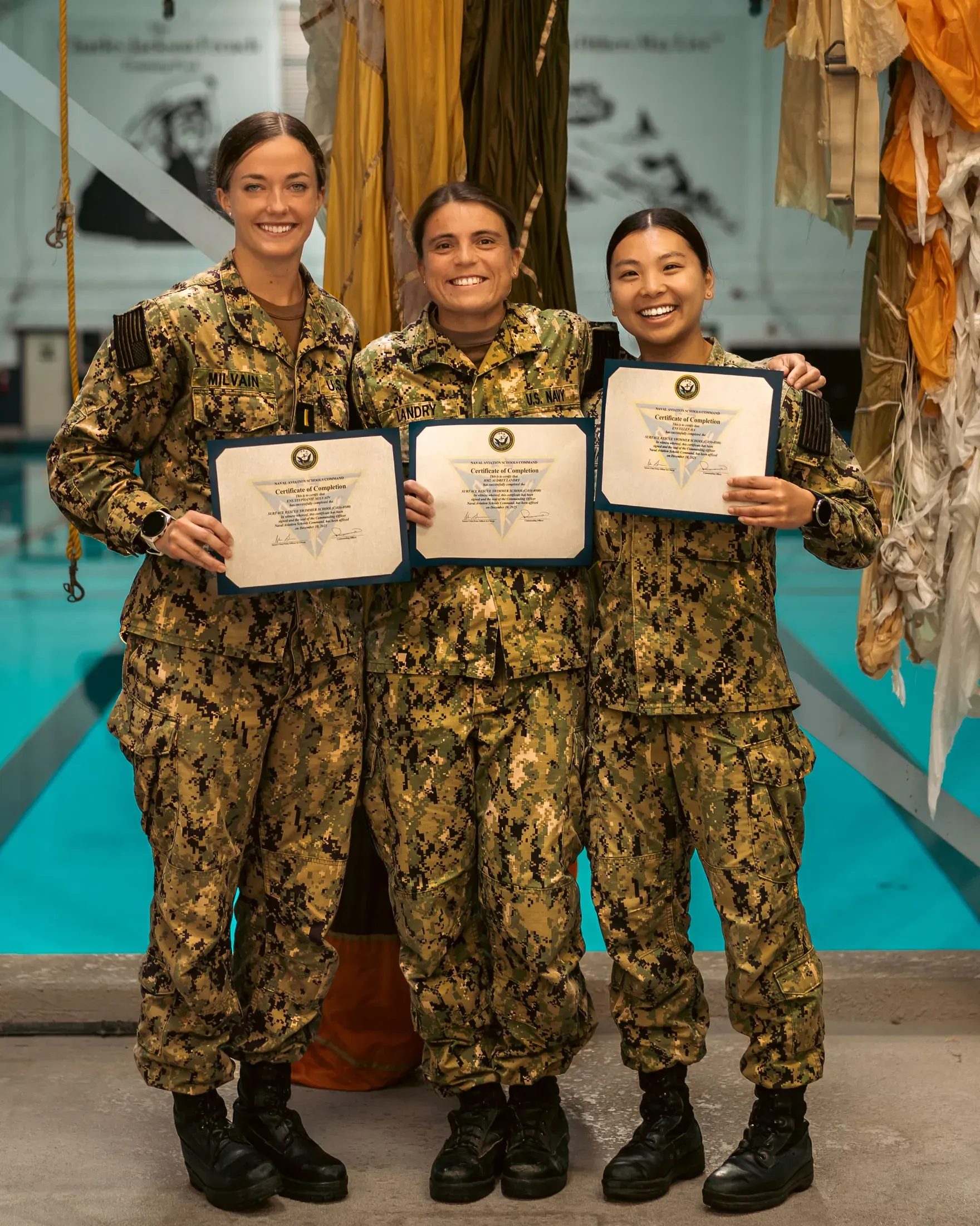 Three sailors in uniform holding award certificates
