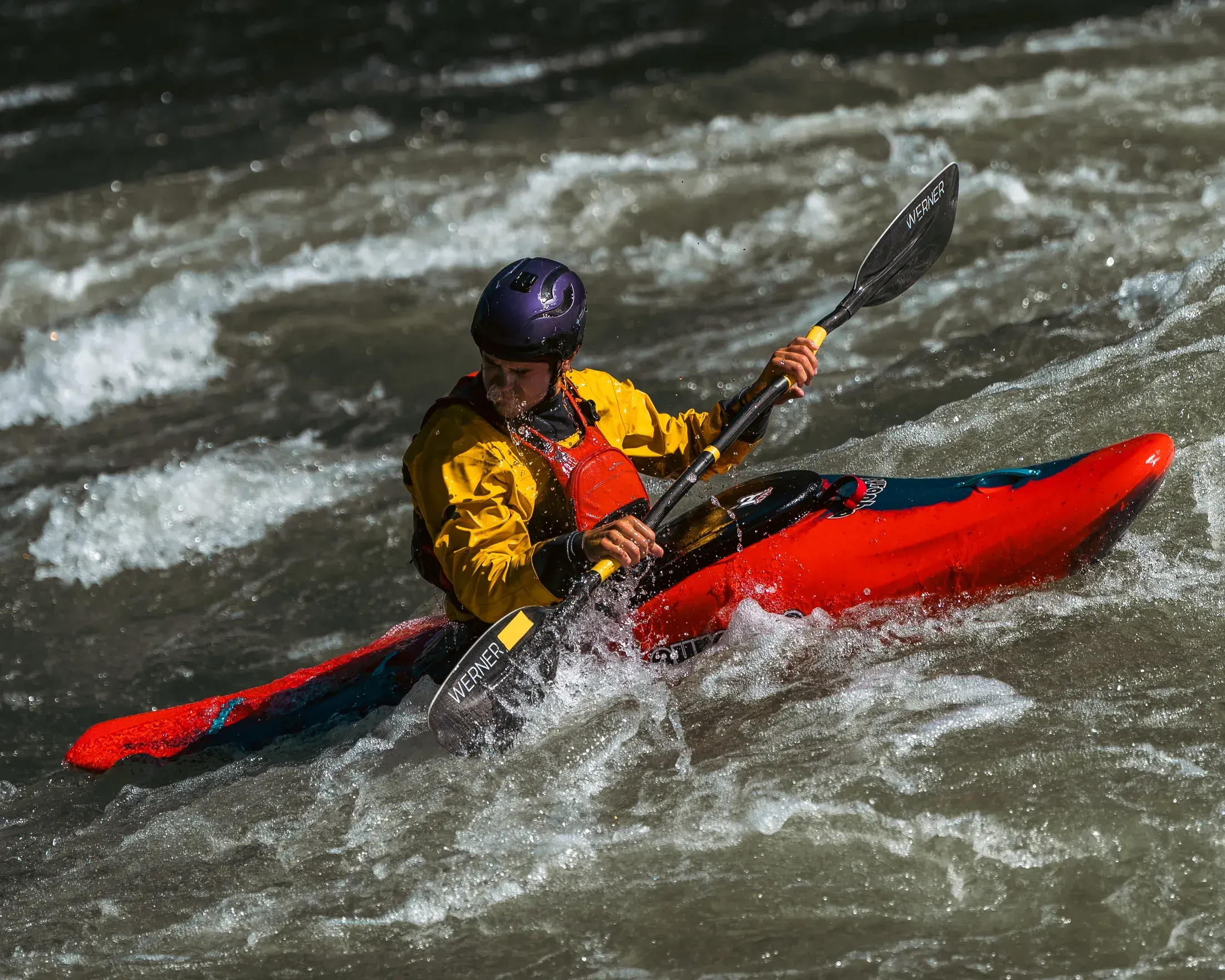 Kayaker in a red boat charging a rapid