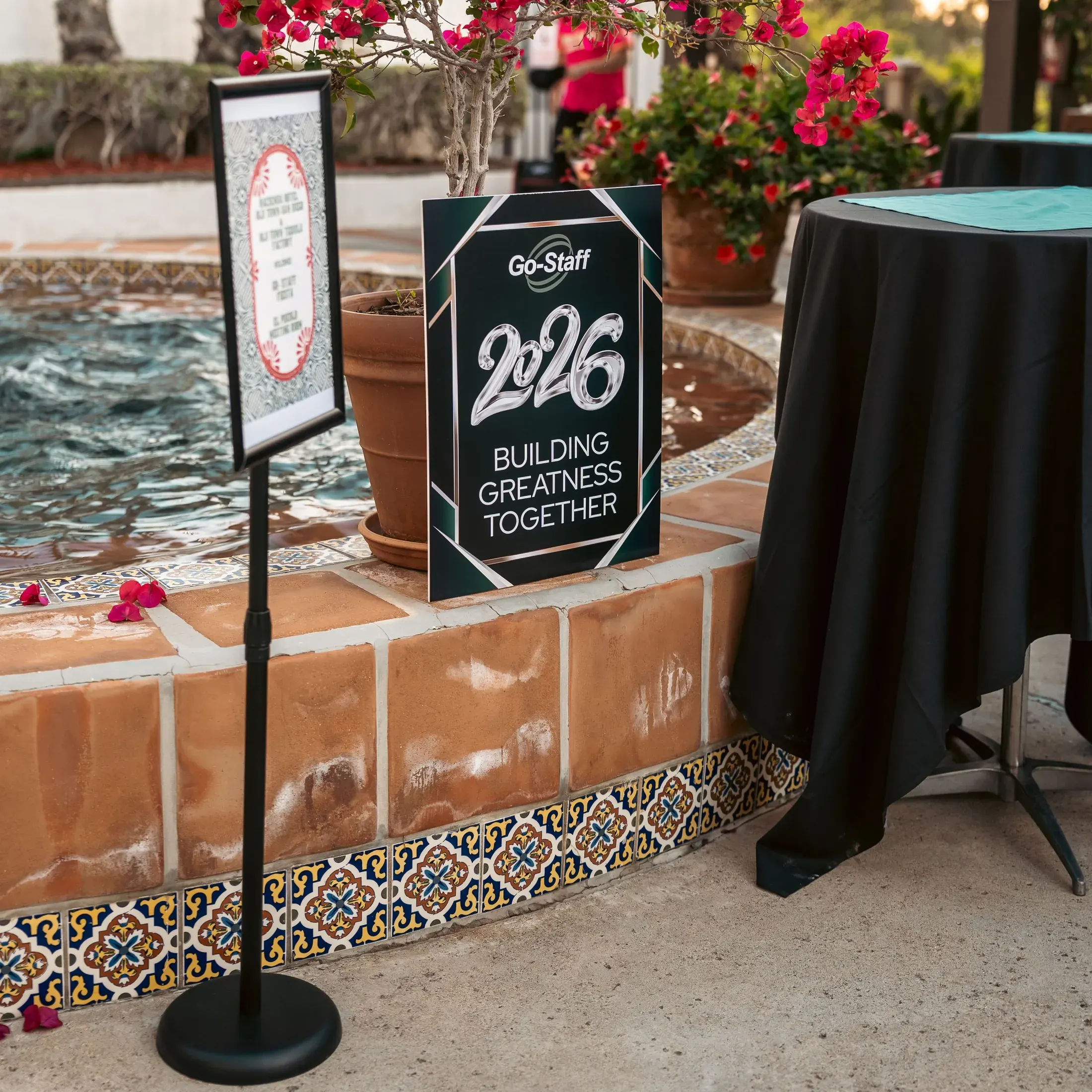 Event welcome sign beside a tiled fountain