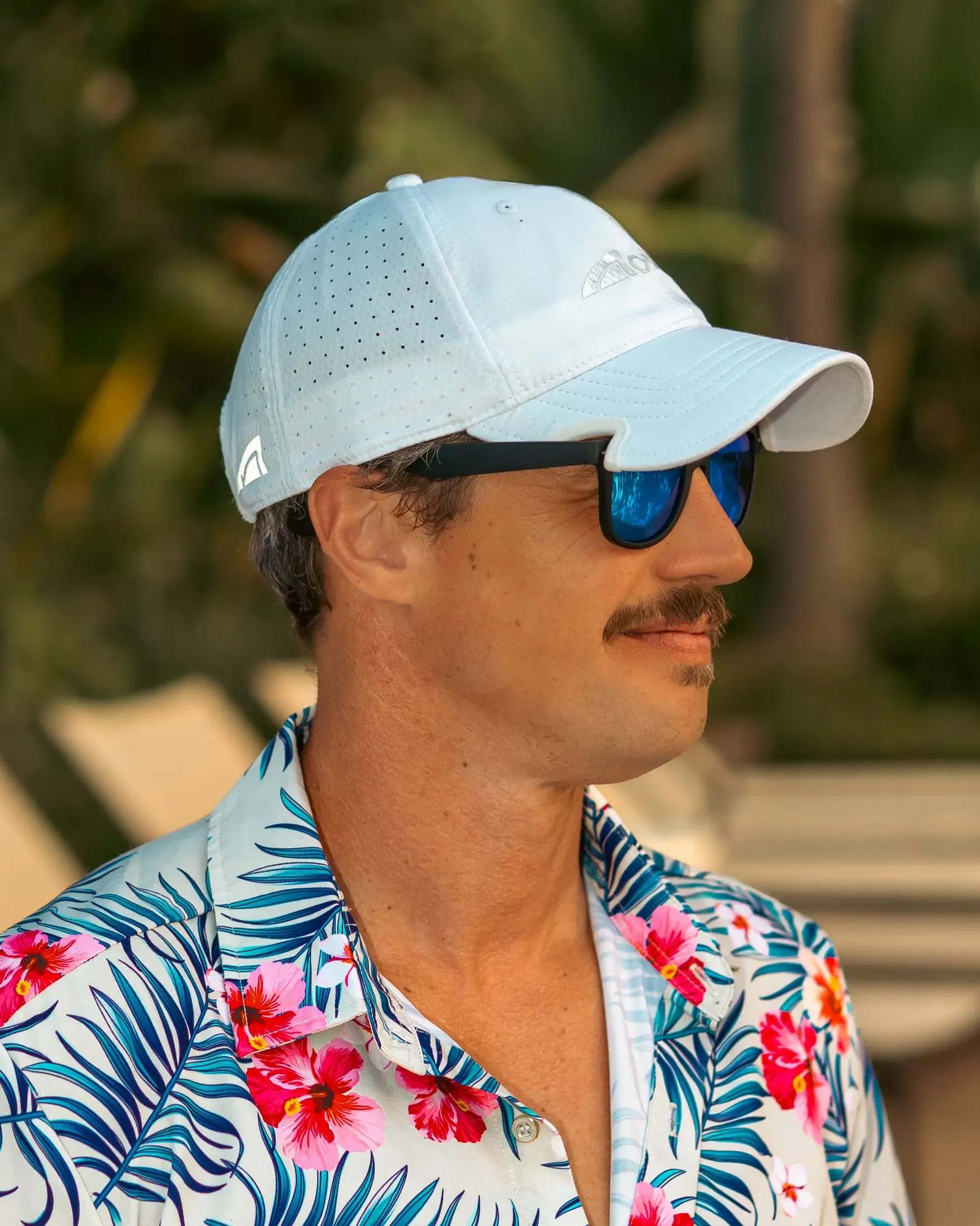 Man in a floral shirt, white cap and sunglasses
