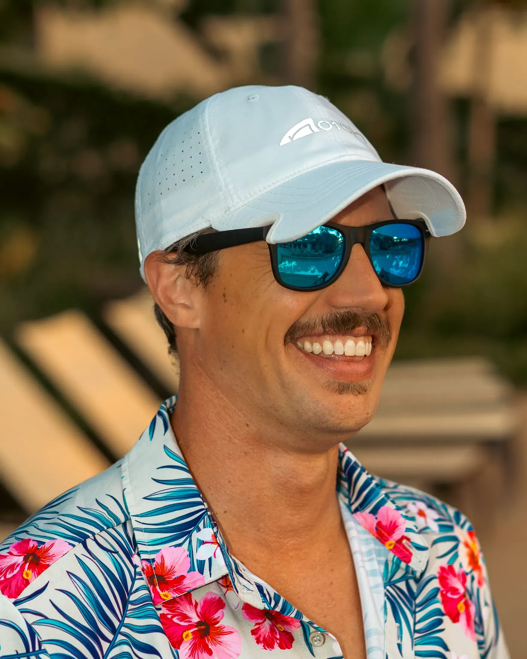 Man in a white cap and floral shirt laughing