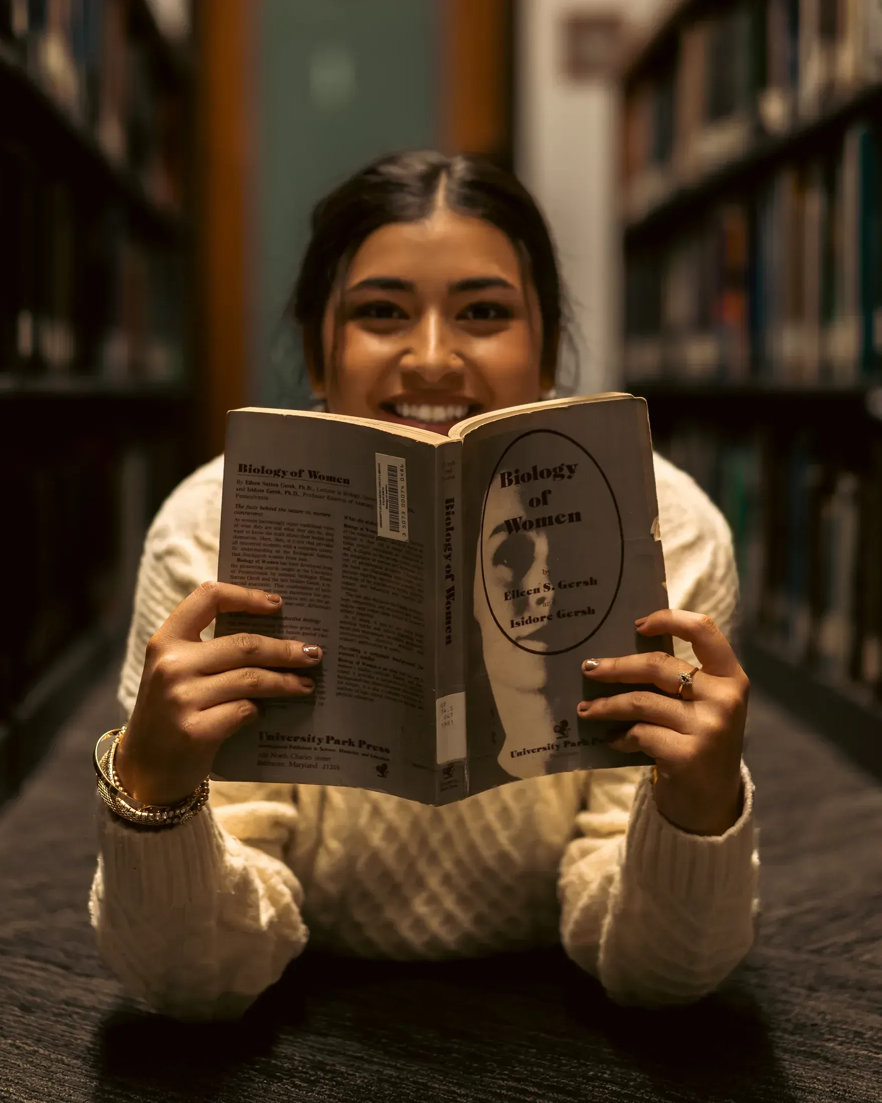 Woman peeking over a book in the library