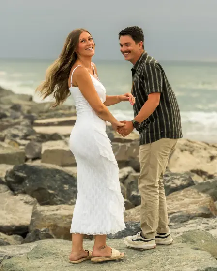 Couple holding hands on the rocks at the beach
