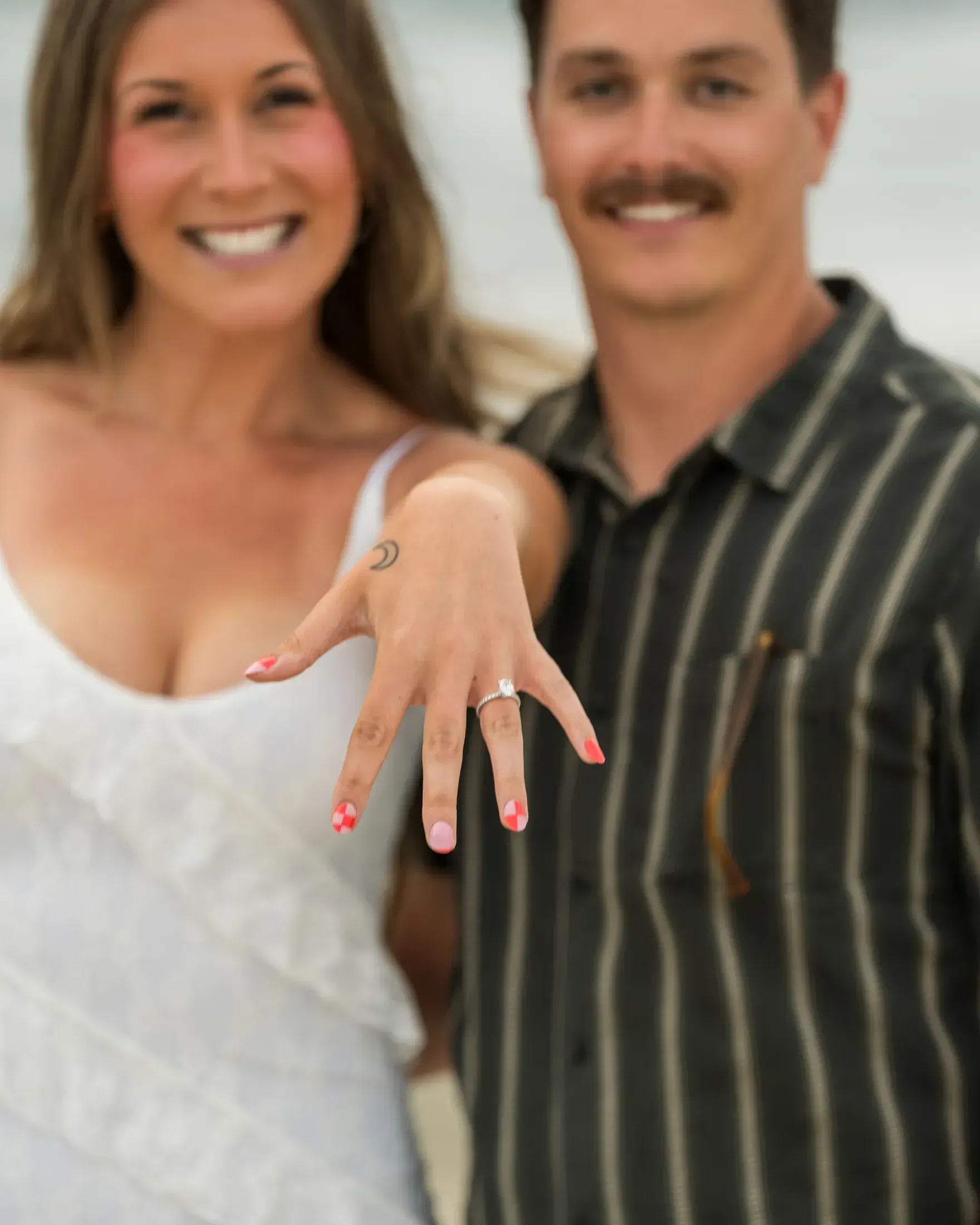 Newly engaged woman showing off her ring beside her fiance