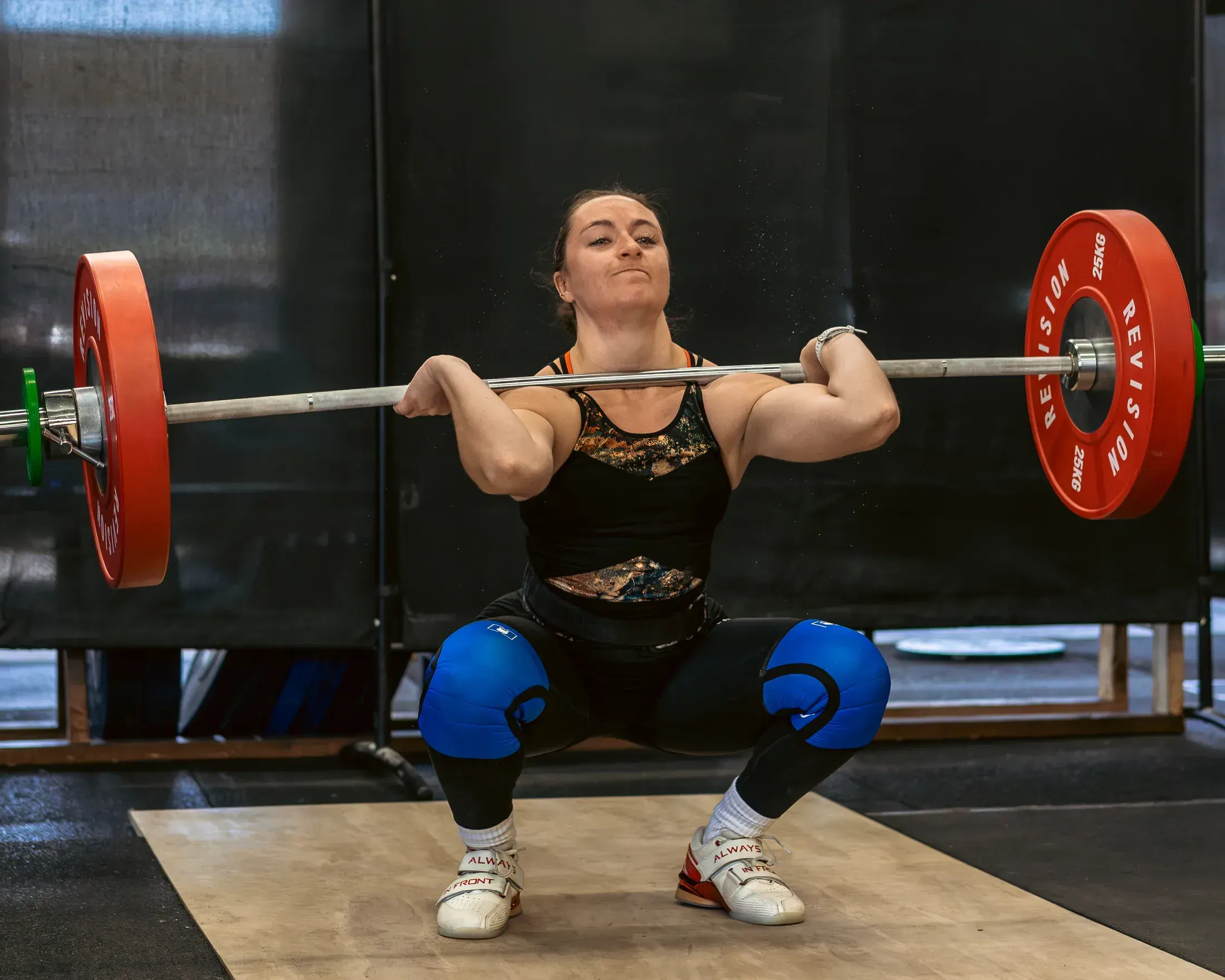 Weightlifter in a front squat with red plates