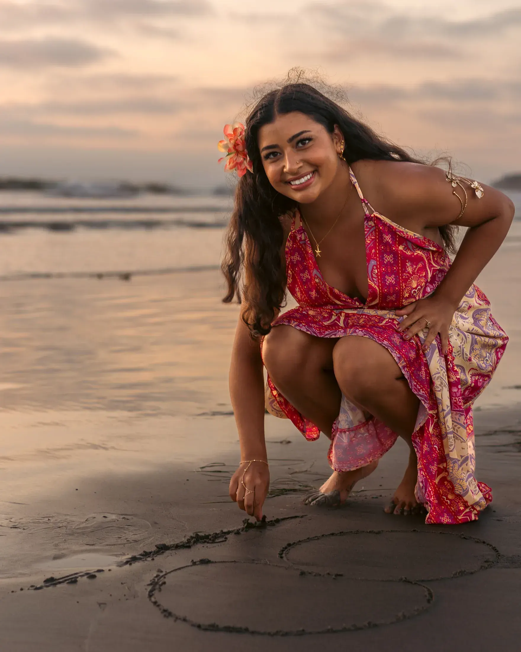 Woman crouching to draw a heart in the wet sand
