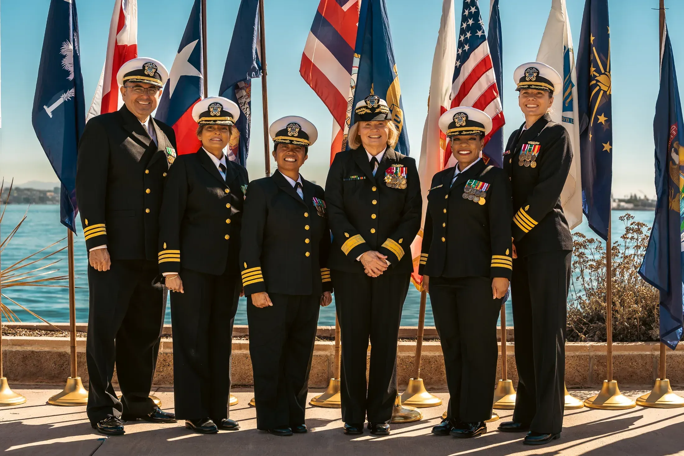 Navy officers in dress blues in front of the state flags