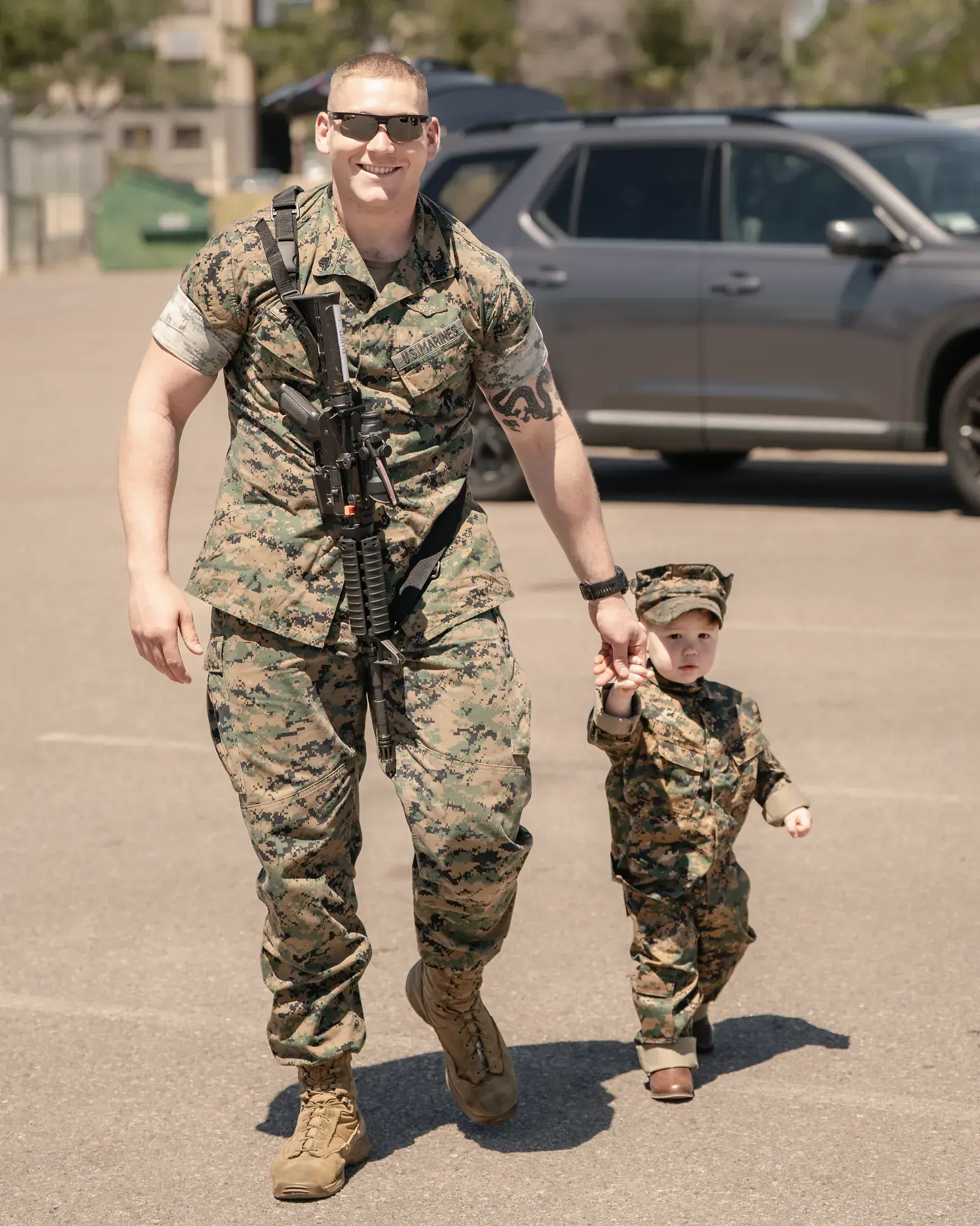 Marine walking hand in hand with his son after a homecoming