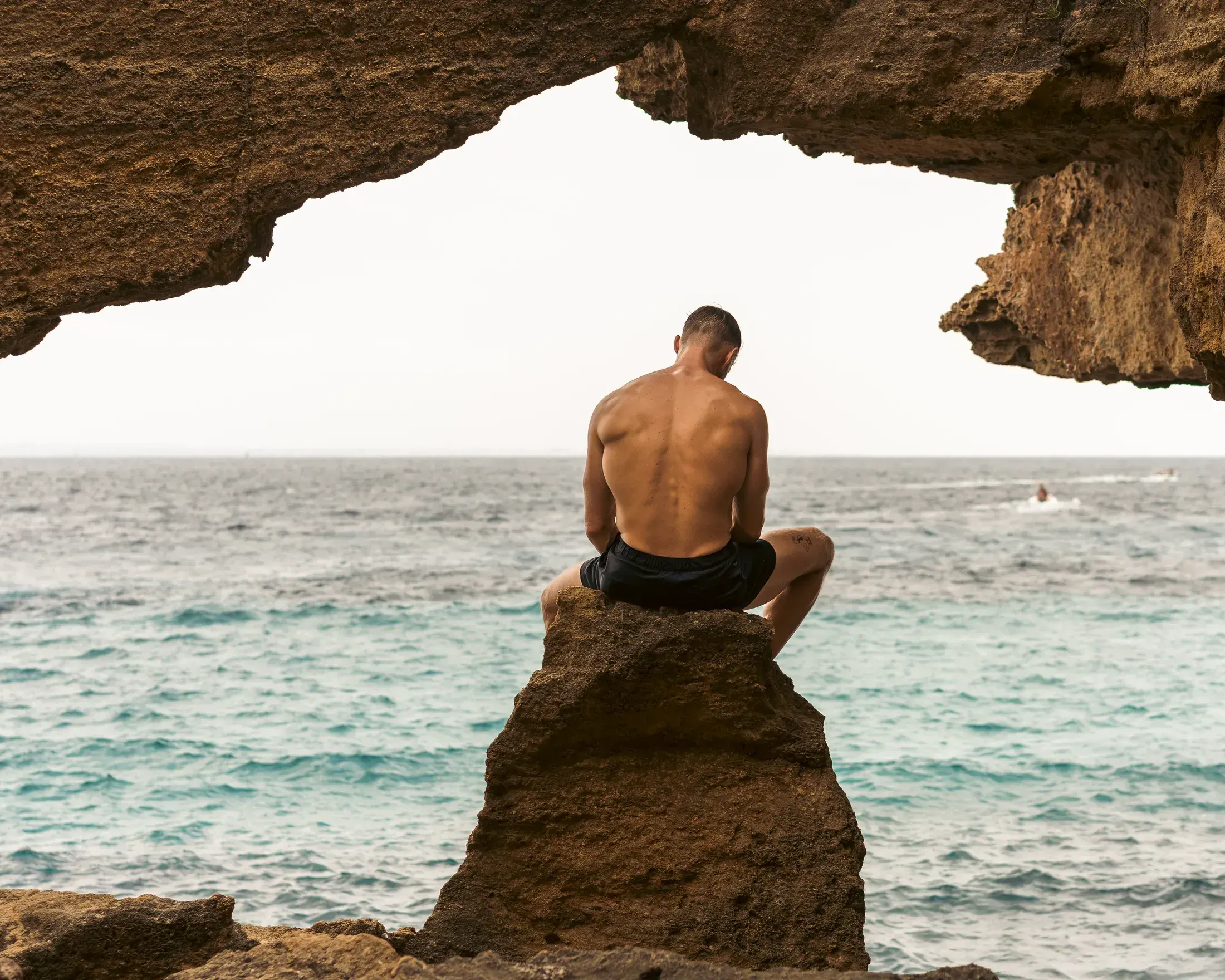 Man sitting on a rock inside a sea cave