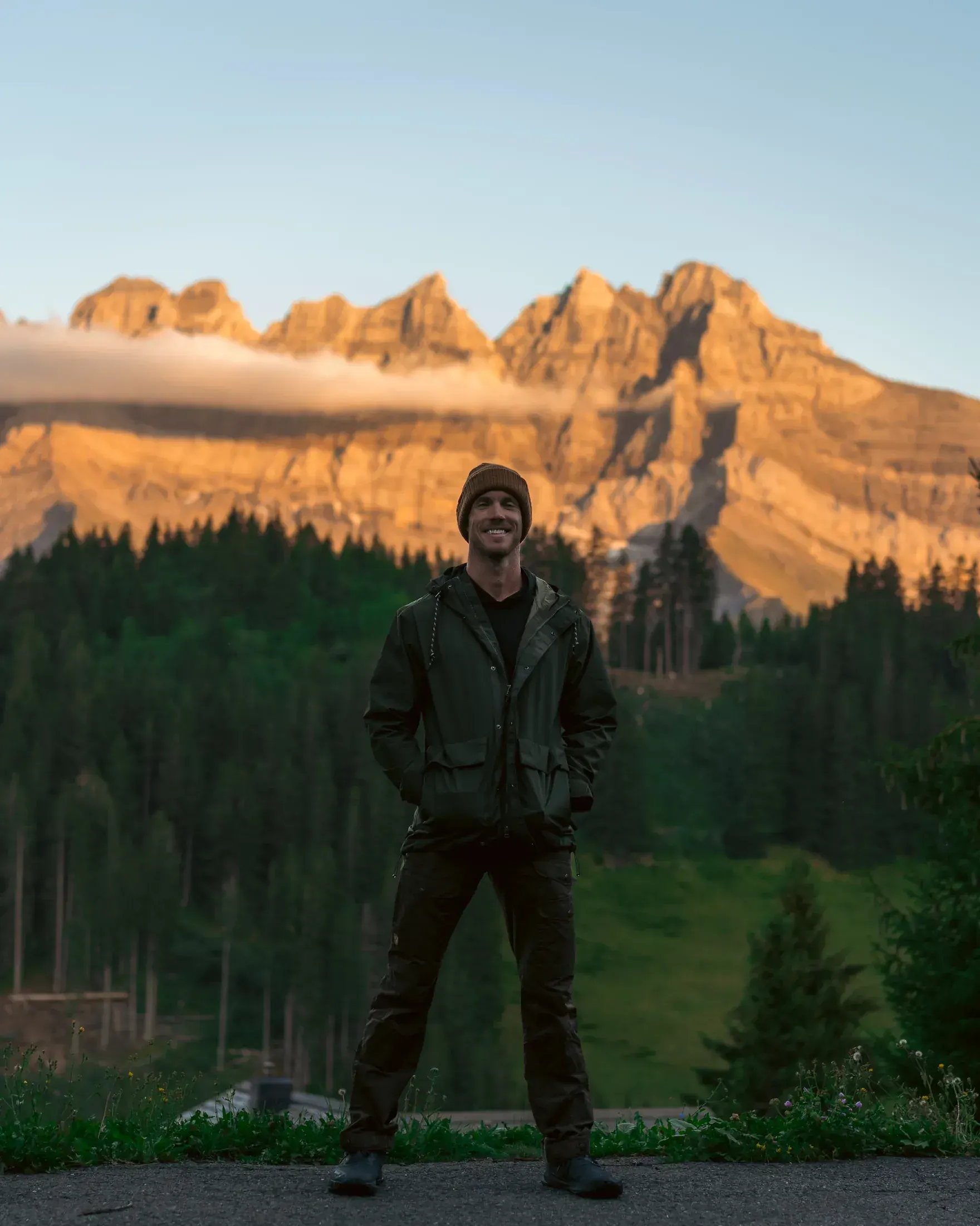 Man in the Alps with sunlit peaks behind him