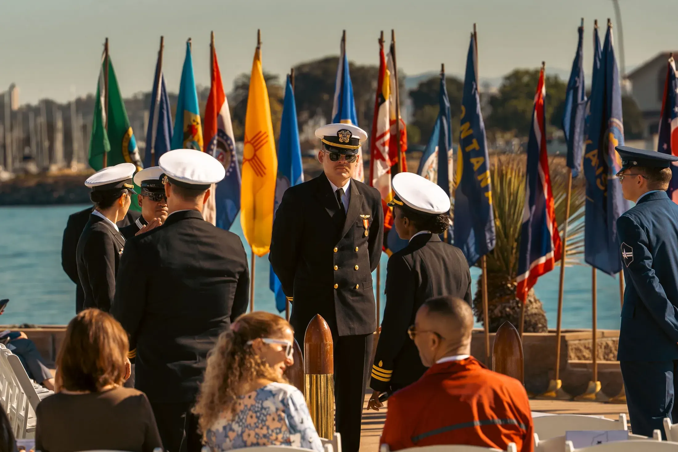 Guests watching a Navy ceremony with flags in the background