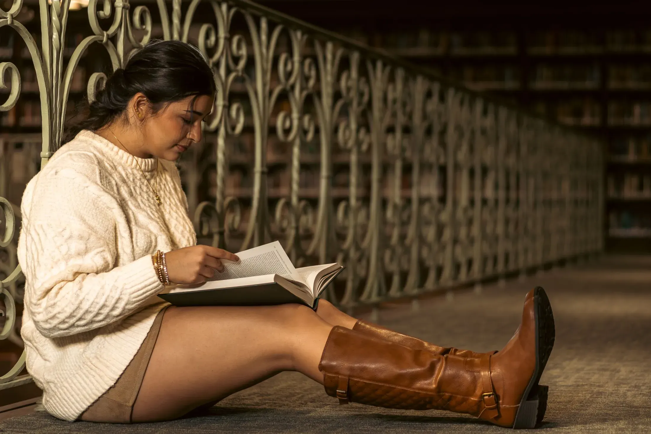 Woman reading a book against a wrought iron gate