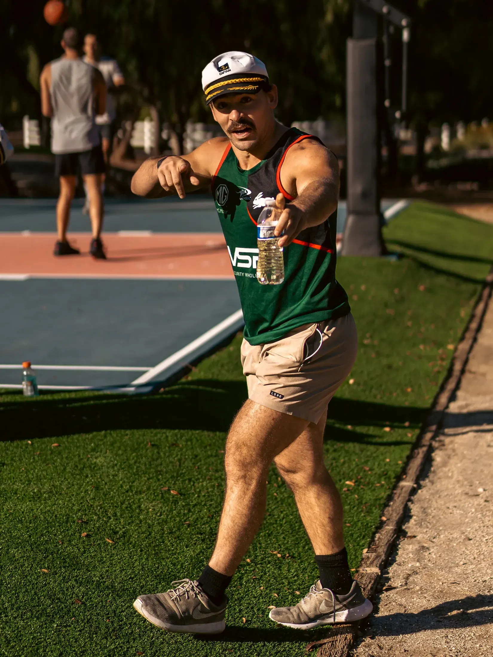 Athlete in a green jersey pointing at the camera on a sports court