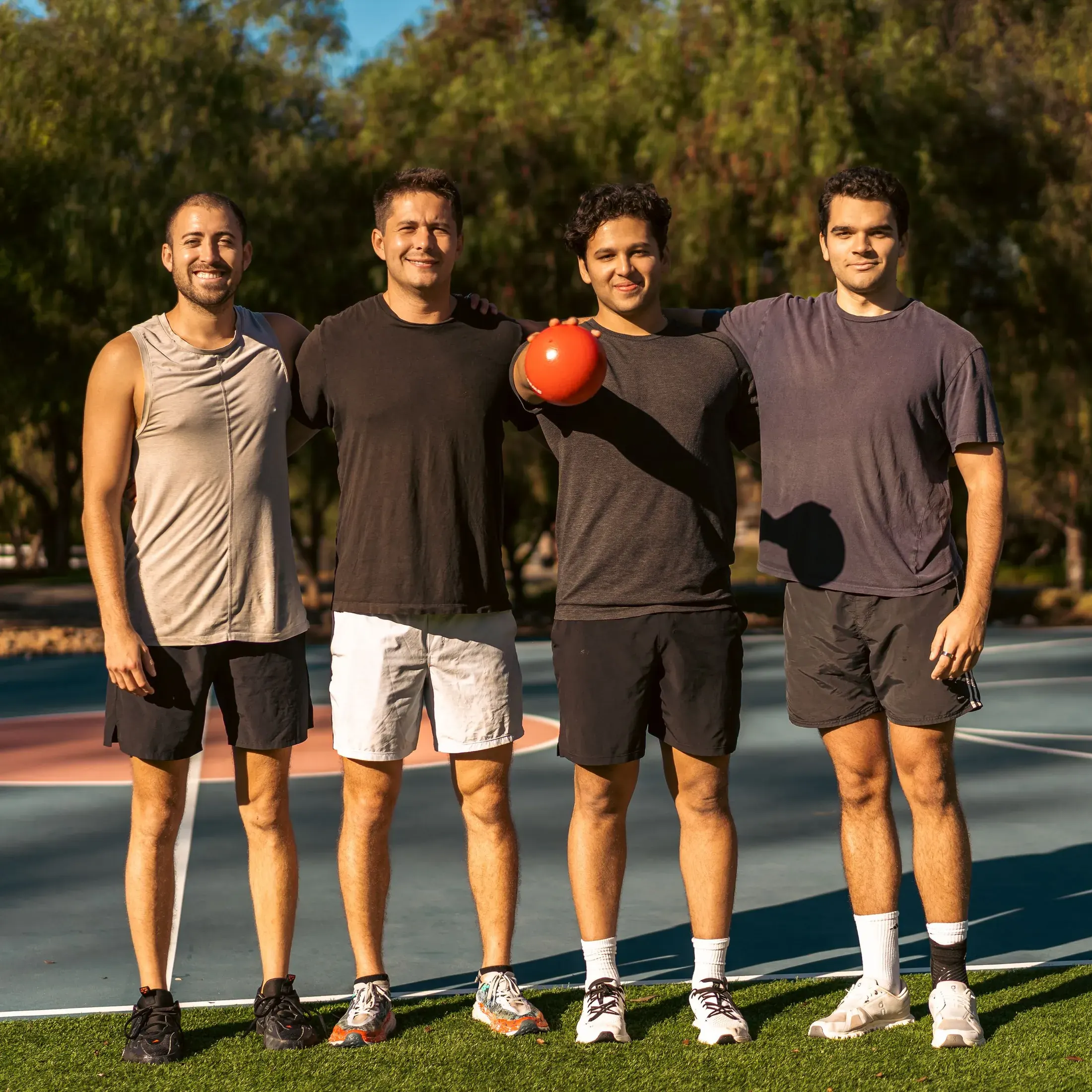 Four friends posing with a ball on a sports court