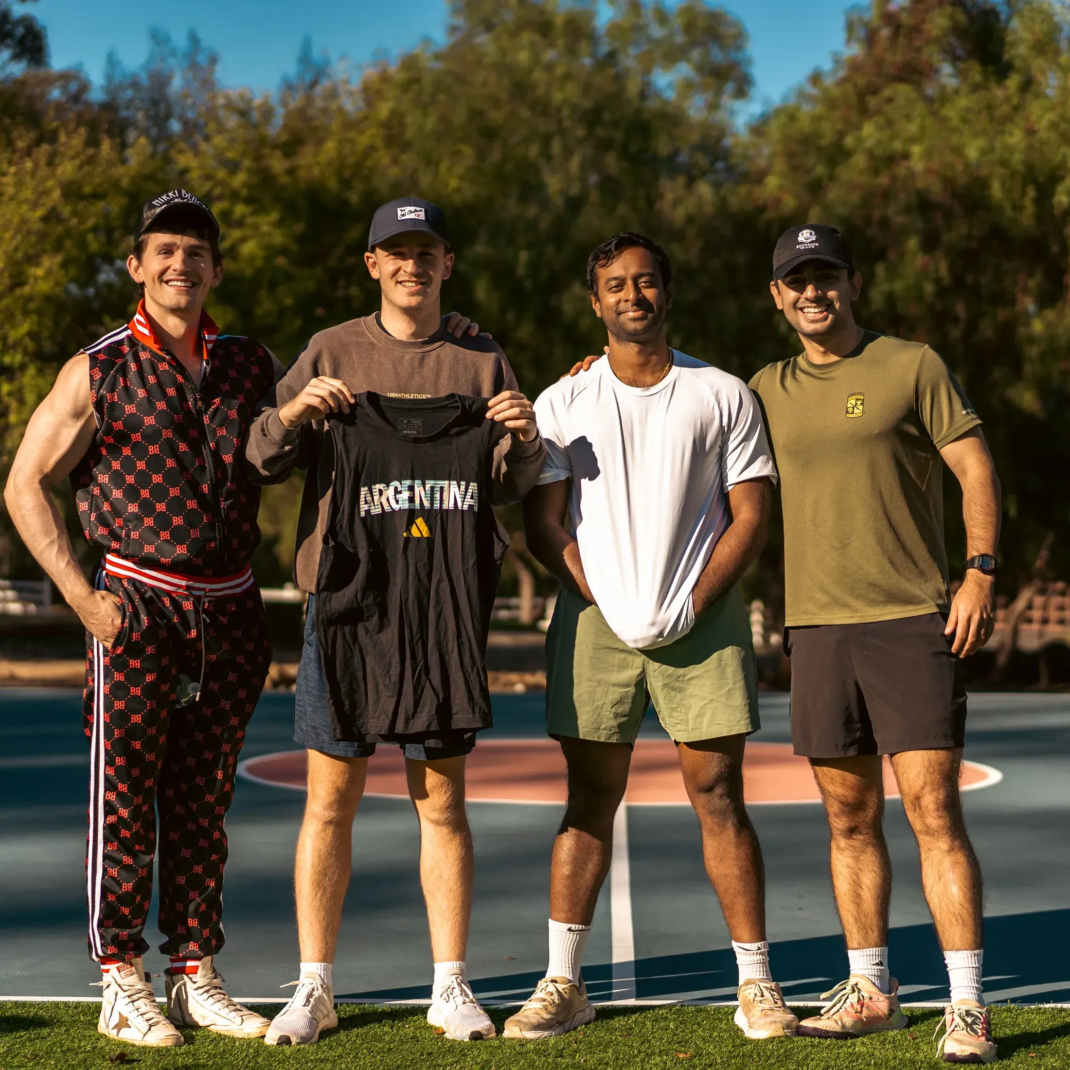 Four men posing on a court at an outdoor event
